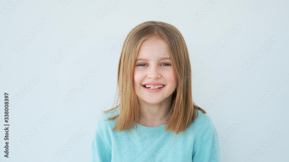 Lovely little girl smiling on white wall background Lovely little girl smiling on white wall background