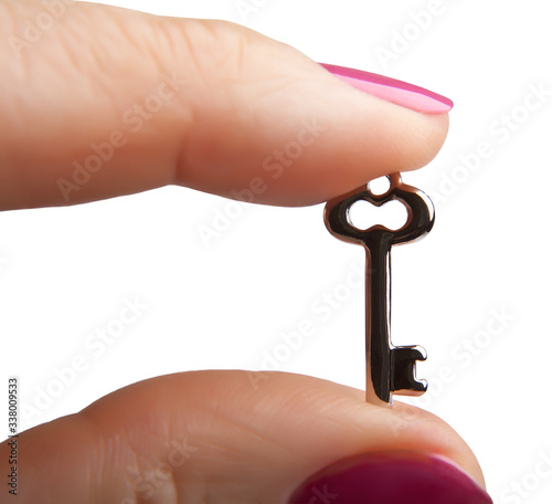 Small metal key between the fingers, isolated on a white background