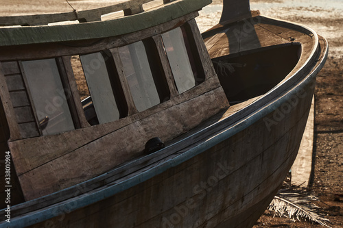 Hull and deckhouse of a wooden boat lying on the shore due to low tide, close-up photo