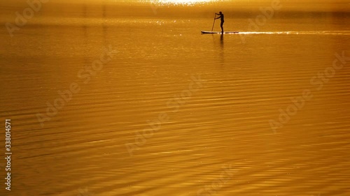 Sup surf on the sunset sky background. Rays of the sun photo