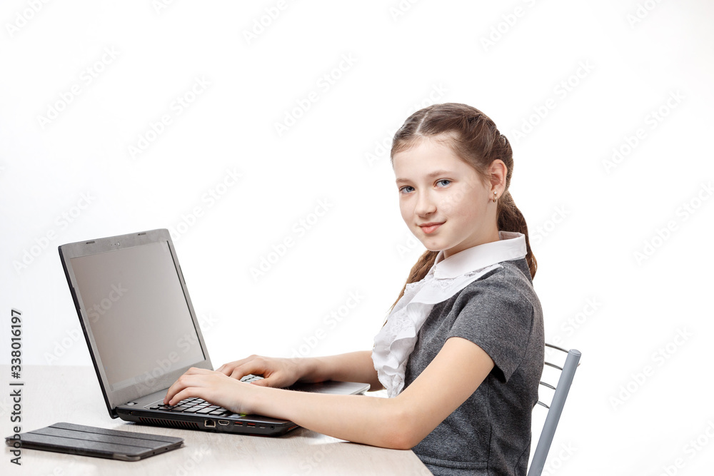 Cute schoolgirl sitting at a laptop on a white background Cute schoolgirl sitting at a laptop on a white background