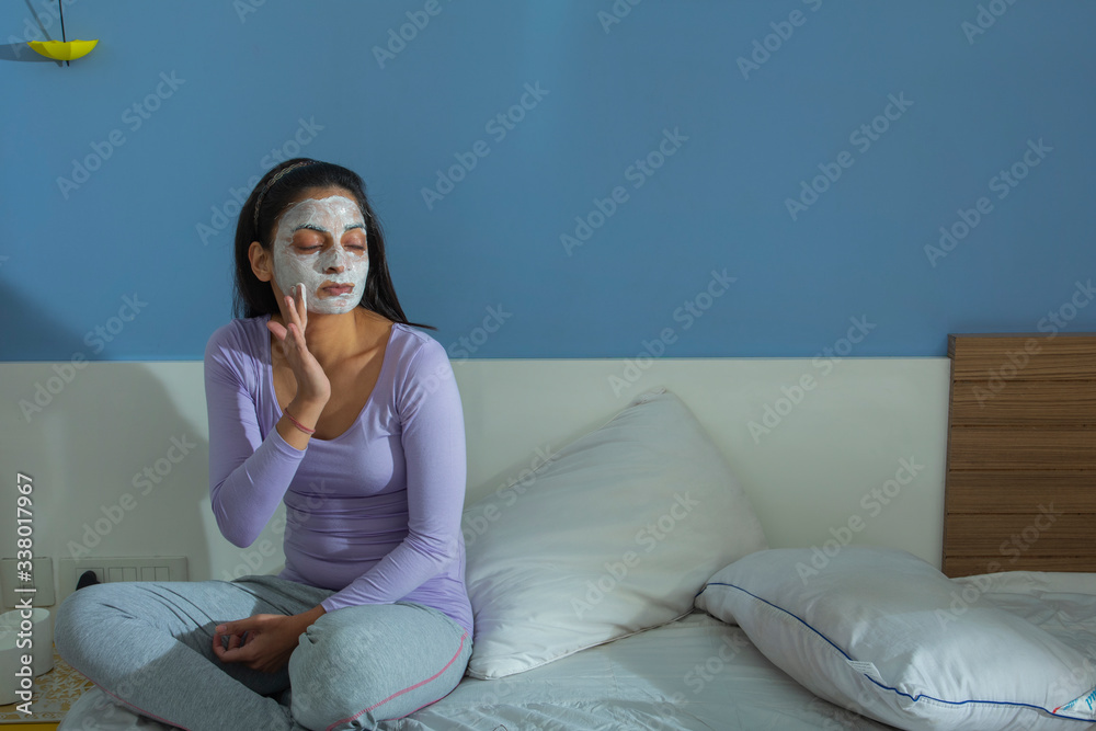 Young woman applying face-pack on her face.
Young woman applying face-pack on her face.