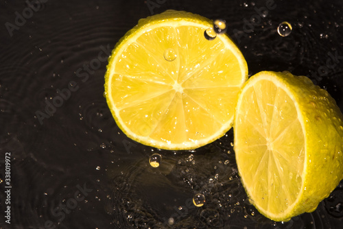 lemon, laim, slices, drops of water on a black background