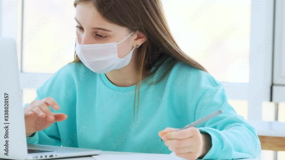 Girl in medical mask studying at home during coronavirus pandemic Girl in medical mask studying at home during coronavirus pandemic
