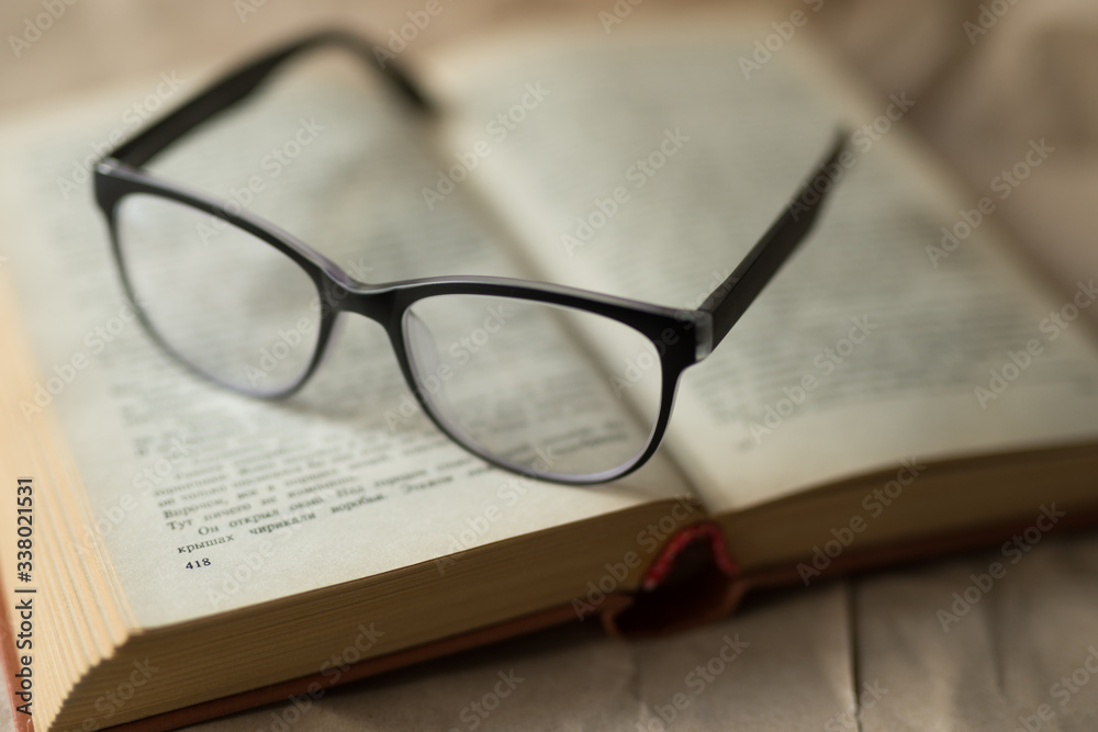 Black glasses lie on an open book, reading, sight, leisure, hobby Black glasses lie on an open book, reading, sight, leisure, hobby