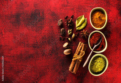 Fototapeta Naklejka Na Ścianę i Meble -  Indian spices seasoning spicy in bowls on a red background, top view.