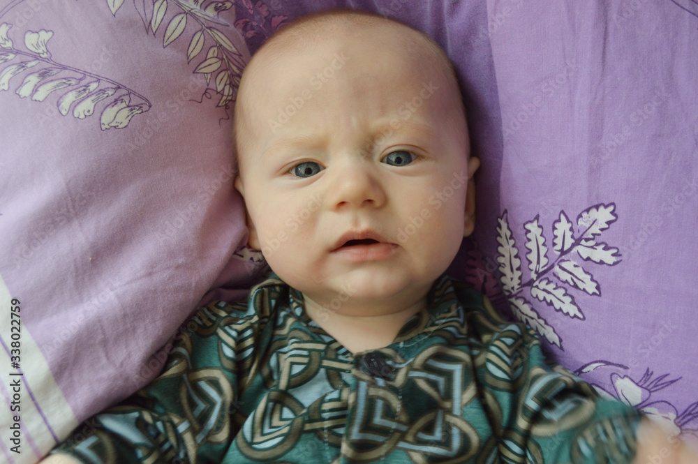 A child on a purple pillow, at home. Smiling, happy. A child on a purple pillow, at home. Smiling, happy.