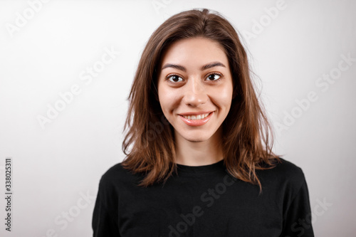 young brunette woman in a black shirt on a white background. emotions. © Yura