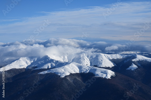 Clouds in snowy mountain tops in winter in Busteni Romania photo