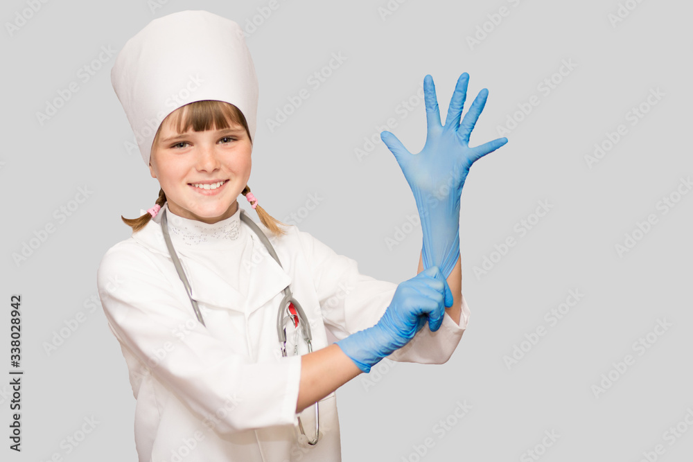 Smiling little girl in medical uniform and protects hands with sterile gloves looking at camera isolated on white Smiling little girl in medical uniform and protects hands with sterile gloves looking at camera isolated on white