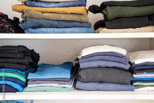 neatly stacked and folded colorful men's clothes in a closet