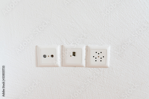 close up view of sockets for television, internet, telephone and electricity on a white wall