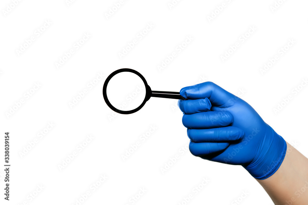 Surgeon's hand in a blue medical glove holding a magnifying glass . The concept of health. Surgeon's hand in a blue medical glove holding a magnifying glass . The concept of health.