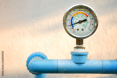 Water pressure gauge on blue plumbing pipe with natural blur background, Free copy space. photo