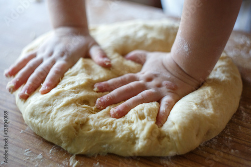 Child's hands knead yeast dough closeup