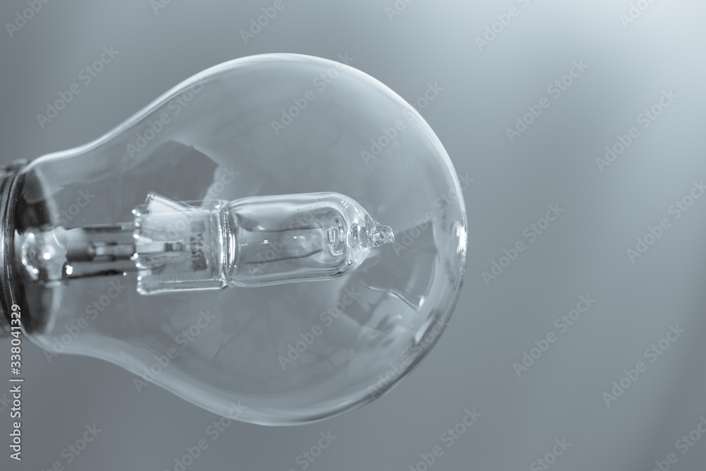 Close up on a transparent light bulb over a grey background. Close up on a transparent light bulb over a grey background.