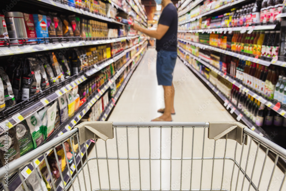 Shopping cart in super market with consumer in protective mask in blur background coronavirus concept.