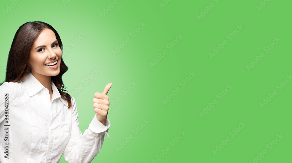 Portrait of happy smiling young excited businesswoman, showing thumb up hand sign gesture. Success in business concept studio shot. Over green color background. Portrait of happy smiling young excited businesswoman, showing thumb up hand sign gesture. Success in business concept studio shot. Over green color background.