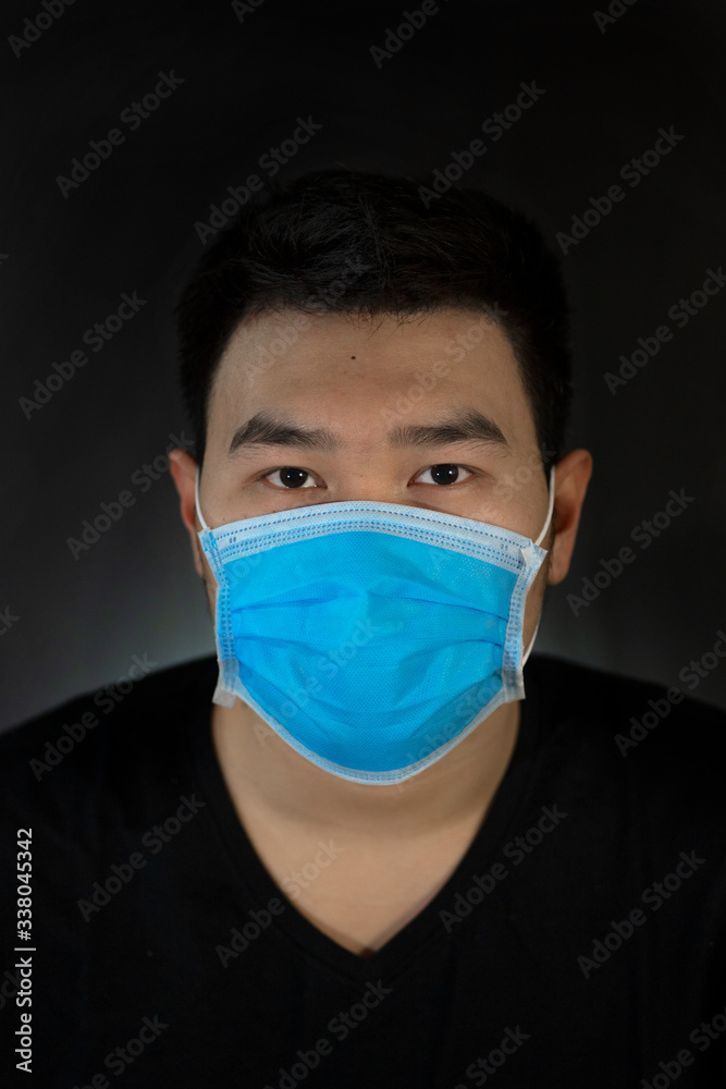Asian men wearing Surgical blue mask in the black background. Protect from virus, sneeze and cough