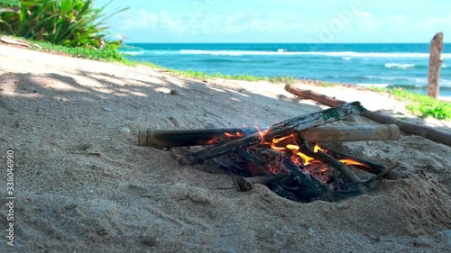 Bonfire on the beach by the ocean on a sunny day. handmade bonfire made of sticks, logs, sand around, blue sea on background photo