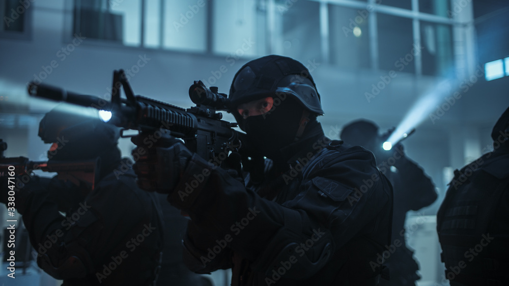 Masked Squad of Armed SWAT Police Officers Stand in Dark Seized Office Building with Desks and Computers. Soldiers with Rifles and Flashlights Surveil and Cover Surroundings. Masked Squad of Armed SWAT Police Officers Stand in Dark Seized Office Building with Desks and Computers. Soldiers with Rifles and Flashlights Surveil and Cover Surroundings.