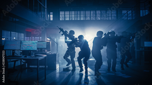 Masked Squad of Armed SWAT Police Officers Storm a Dark Seized Office Building with Desks and Computers. Soldiers with Rifles and Flashlights Move Forwards and Cover Surroundings. © Gorodenkoff