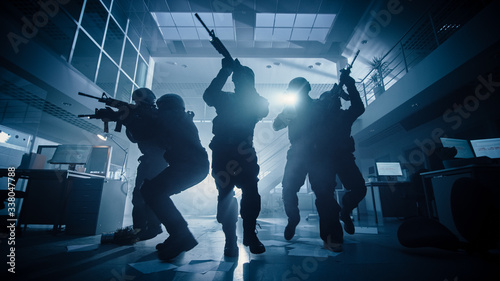 Quadro em tela Masked Team of Armed SWAT Police Officers Move in a Hall of a Dark Seized Office Building with Desks and Computers