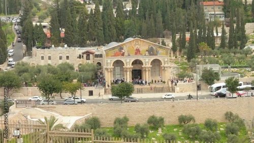 The church of All Nations and The Garden of Gethsemane on Olive Mountain in Jerusalem. Christianity religious sacred places. Tourists people visiting. Long shot.