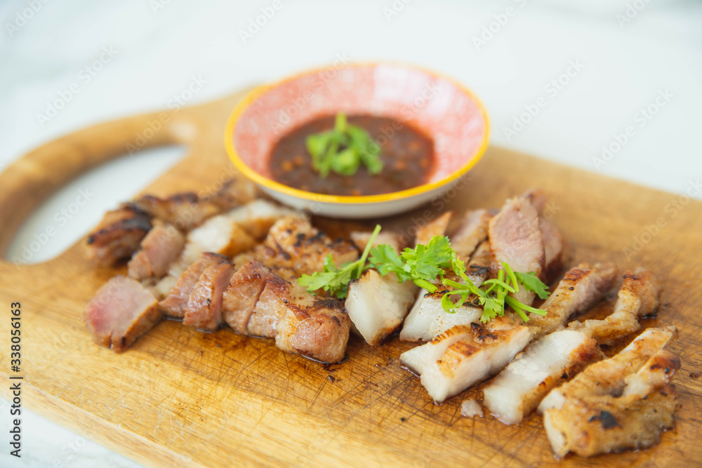 Thai grilled pork neck marinated in the hot sauce from the grill. Tasty slice grilled pork on wooden board,thai food