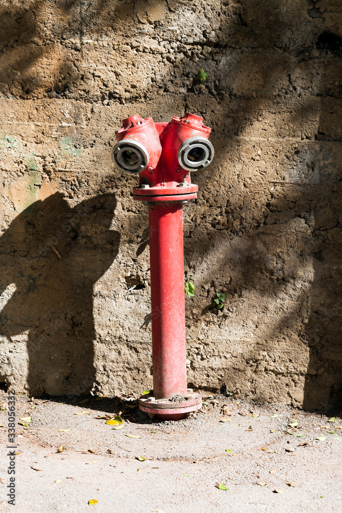 Fire Hydrant. Rusty water pump surrounded by lush vegetation. Red traditional fire hydrant on side walk, for fireman use Fire Hydrant. Rusty water pump surrounded by lush vegetation. Red traditional fire hydrant on side walk, for fireman use