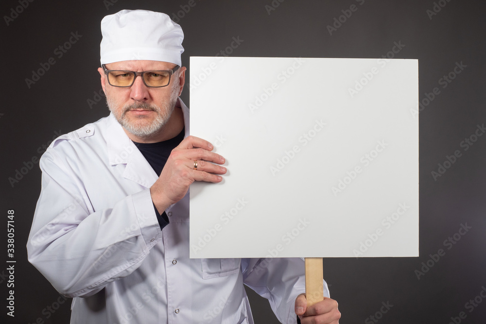 Doctor with a banner in his hands. Medic demonstrates a slogan on a banner. Concept - a doctor calls for something. Place for the slogan on the banner. Doctors advocate better working conditions Doctor with a banner in his hands. Medic demonstrates a slogan on a banner. Concept - a doctor calls for something. Place for the slogan on the banner. Doctors advocate better working conditions