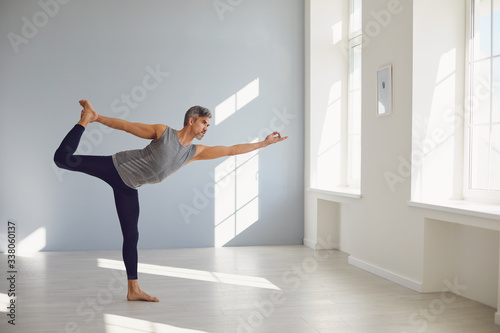 Yoga man. A man is practicing yoga balance in a gray room.