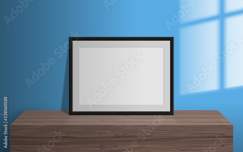 empty blank picture frame on wooden table window light effect on the wall mock up 