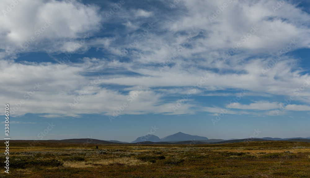 great visibility over an upland plain in sweden with a mountain range in background an blue sky with little clouds