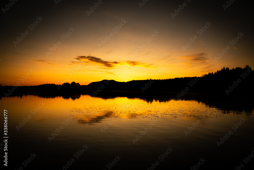 warm sunset of a lake in sweden with yellow colors and reflections on the water