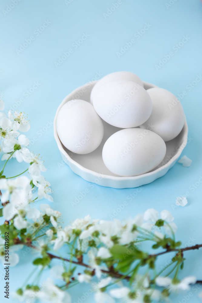 White eggs in bowl on blue background with flowers White eggs in bowl on blue background with flowers