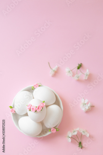 White eggs in bowl on pink background with flowers