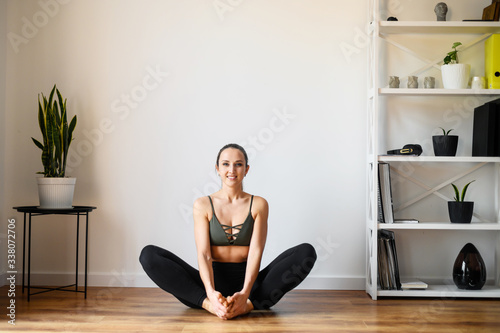 Young positive woman is practicing yoga at home
