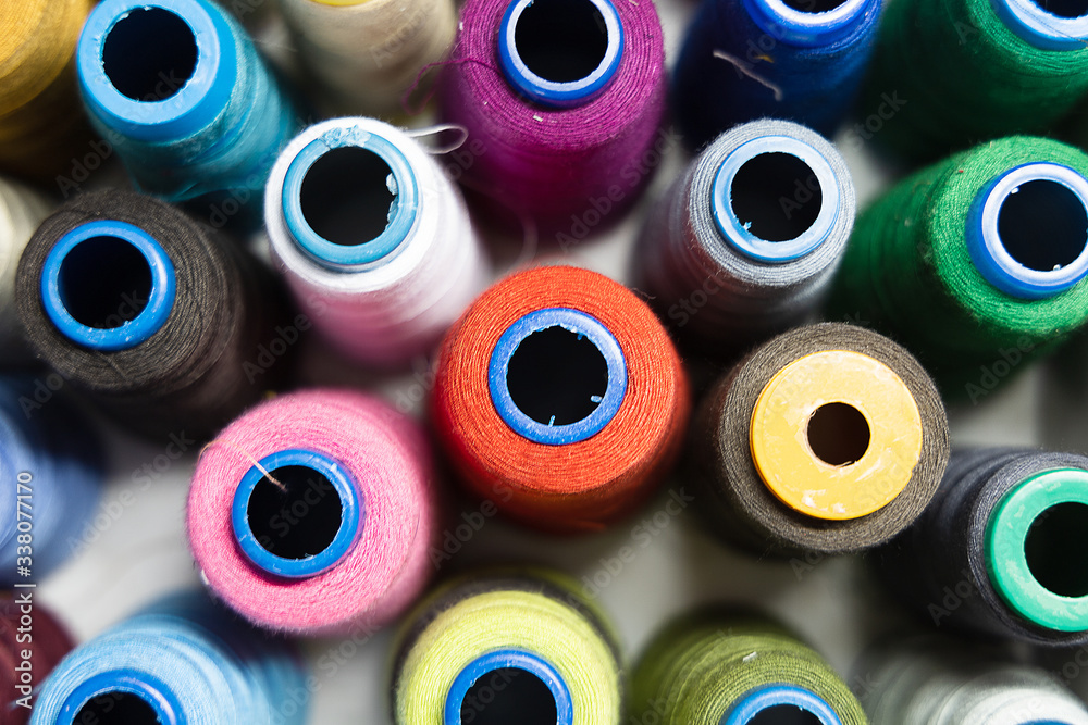 A pile of sewing reels with threads of different colors. Closeup. Top view. Background A pile of sewing reels with threads of different colors. Closeup. Top view. Background
