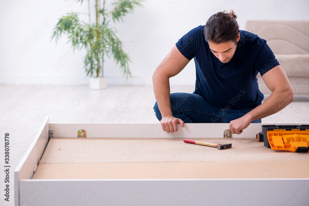 Young male contractor installing furniture at home Young male contractor installing furniture at home