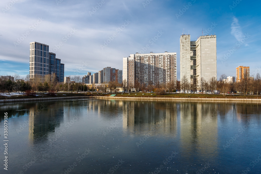 Landscape with lake in the Friendship park in Moscow. Russia. Buildings are reflected in the water