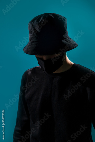 The mysterious guy in the shadow in a black bucket hat and black jacket lowered his head