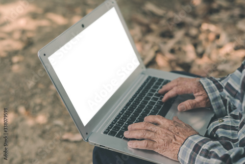 Asian farmer working through laptop and with an blank screen on the farm