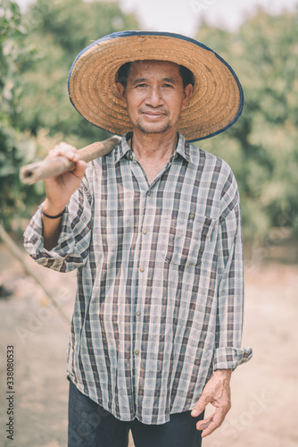 An Asian farmer stands on his farm.