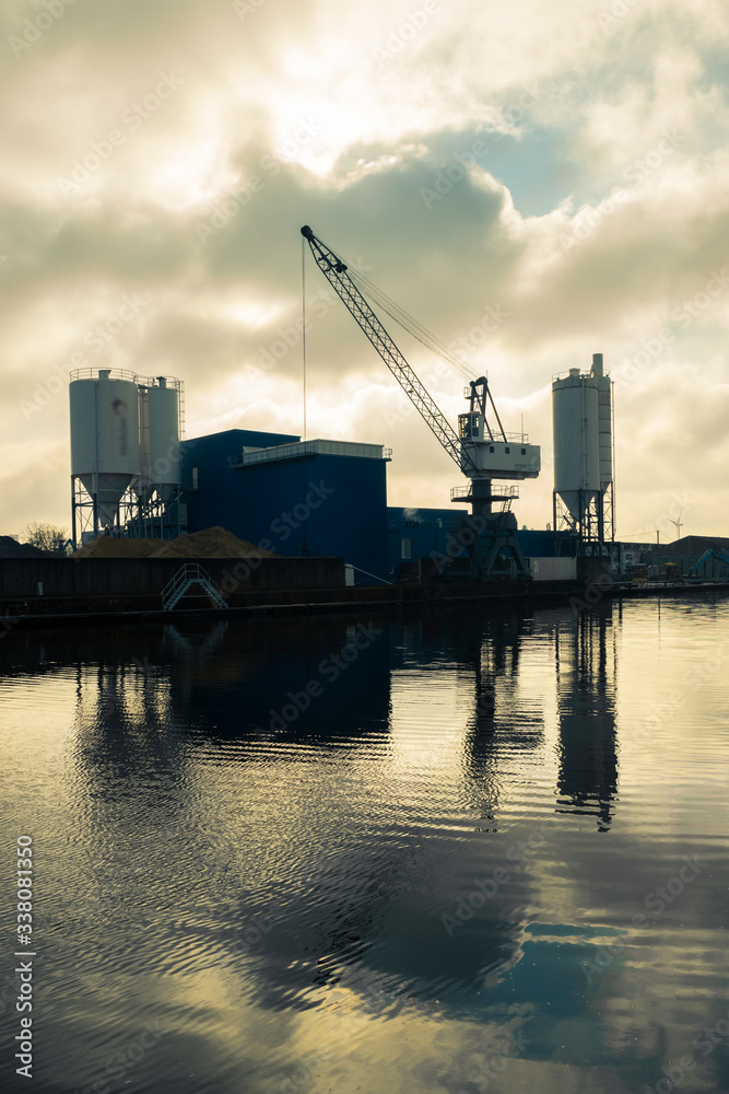 Silhouette of mortar and cement industry construction with large crane along a river