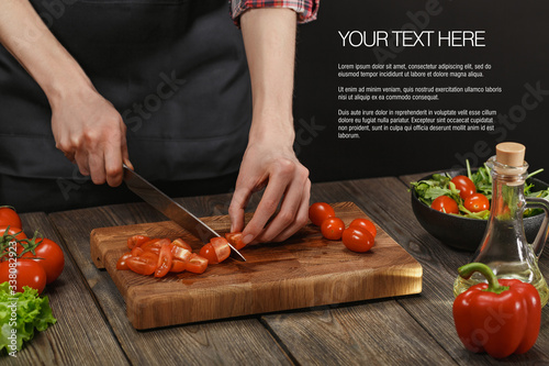 Woman cooking fresh healthy salad. Female hands cutting vegetables on board on wooden table with sample text.