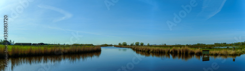 Broad panoramic view on water and grassland at a sunny afternoon in spring