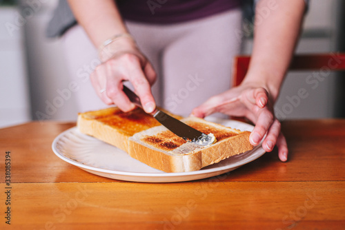 two hands spreading butter on toast