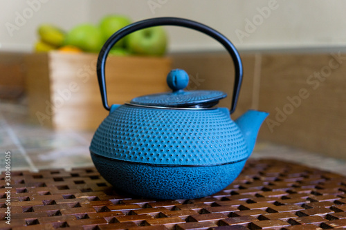 blue japanese teapot with green apples in the background