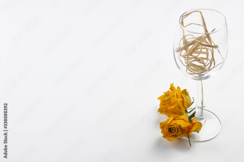 A wine glass and dried roses isolated on white background. Table decoration. Copy space. A wine glass and dried roses isolated on white background. Table decoration. Copy space.